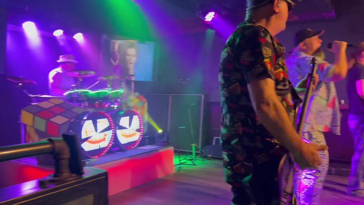 Dangerous Cheese performing on the Revival Room stage under pink and green lights in June 2026